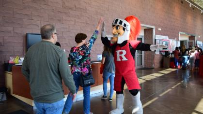 A student high-fives the Rutgers Scarlet Knight mascot