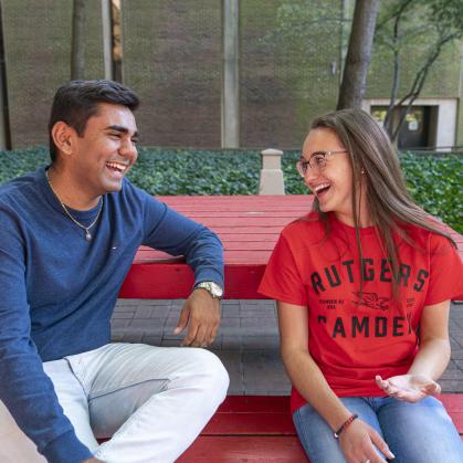 Two students sitting on at a picnic table talking.