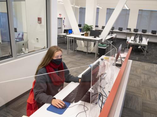 female student in mask sitting at computer