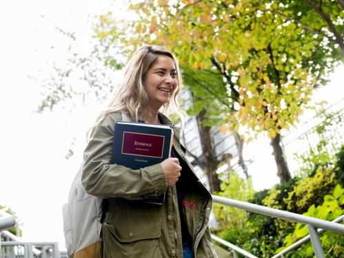 A smiling student walks on campus