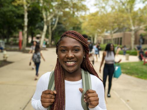 A young woman on a college campus looks at the camera