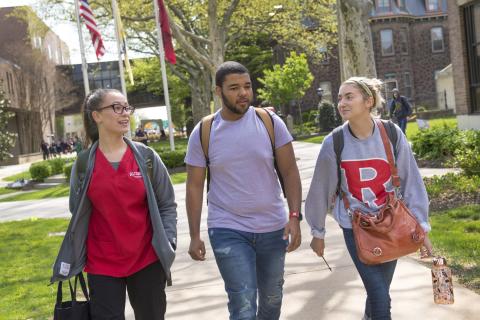 Three students walk on a college campus