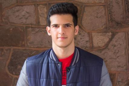 A young person stands in front of a wall